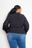 Woman wearing black blouse with punched sleeves, showcasing back view, paired with blue jeans for a stylish plus-size outfit.